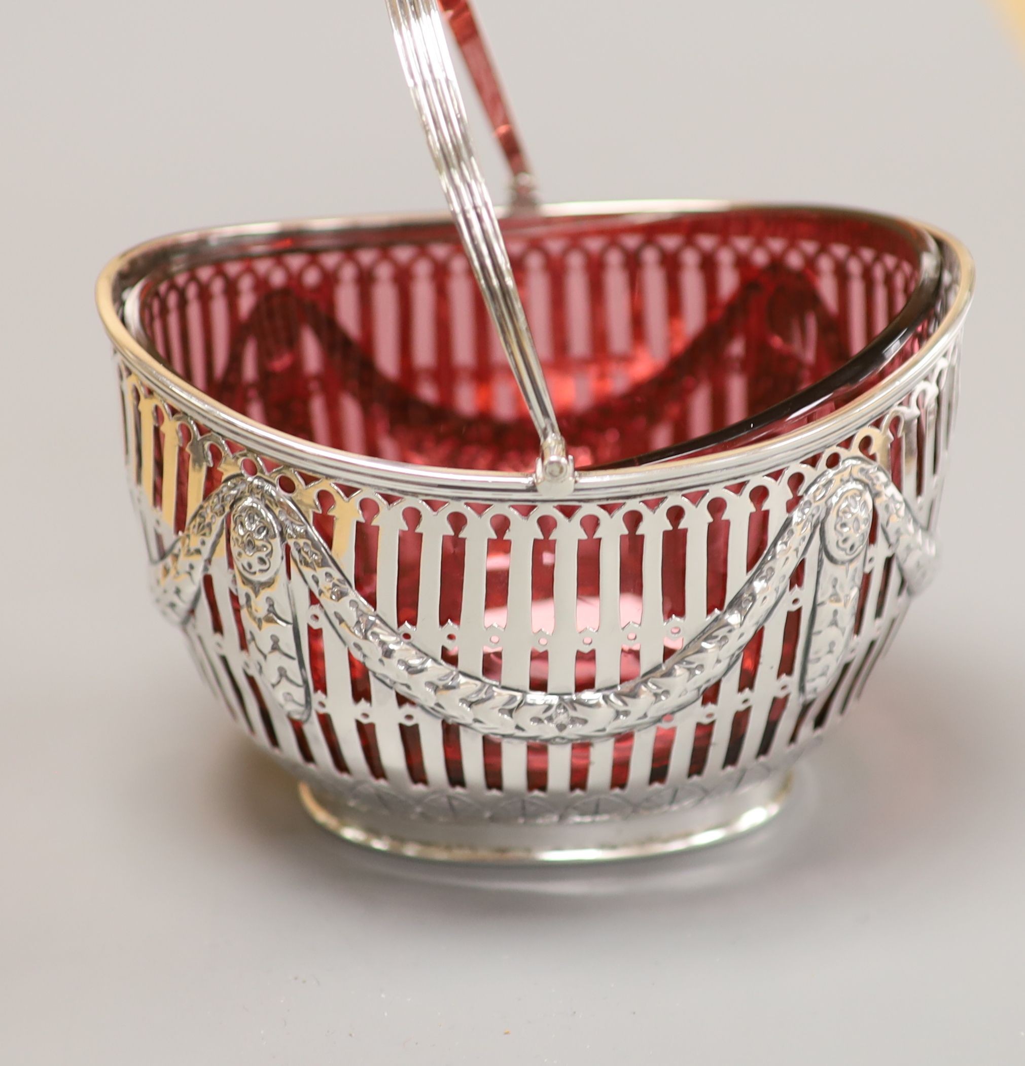 A late Victorian pierced silver oval sugar basket, with cranberry glass liner, Nathan & Hayes, Chester, 1898, height 83mm, 150 grams.